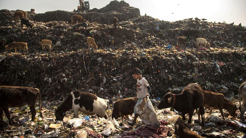 Imradul Ali, 10, left, and his mother Anuwara Beghum, 30, take a break as they look for recyclable material at a landfill on the outskirts of Gauhati, India, Thursday, Feb. 4, 2021. Once school is done for the day, Ali, rushes home to change out of his uniform so that he can start his job as a scavenger in India’s remote northeast. Coming from a family of scavengers or “rag pickers,
