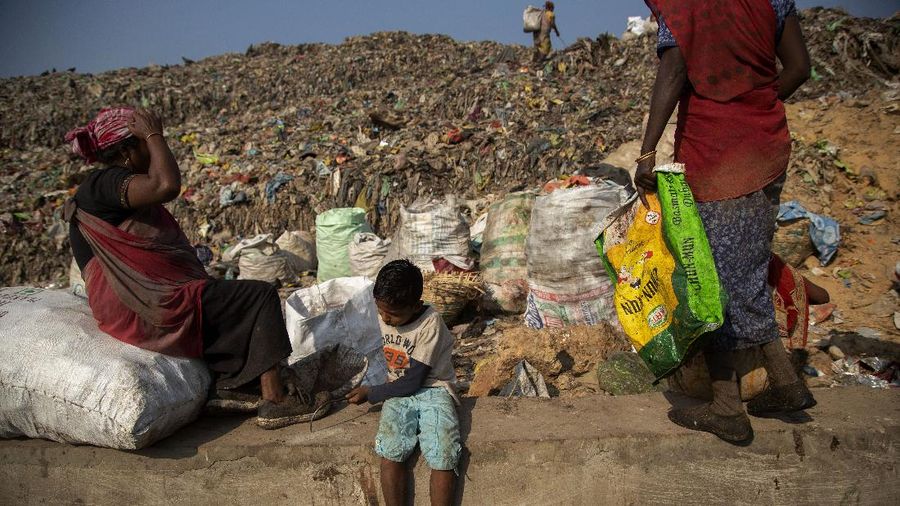 Imradul Ali, 10, left, and his mother Anuwara Beghum, 30, take a break as they look for recyclable material at a landfill on the outskirts of Gauhati, India, Thursday, Feb. 4, 2021. Once school is done for the day, Ali, rushes home to change out of his uniform so that he can start his job as a scavenger in India’s remote northeast. Coming from a family of scavengers or “rag pickers,