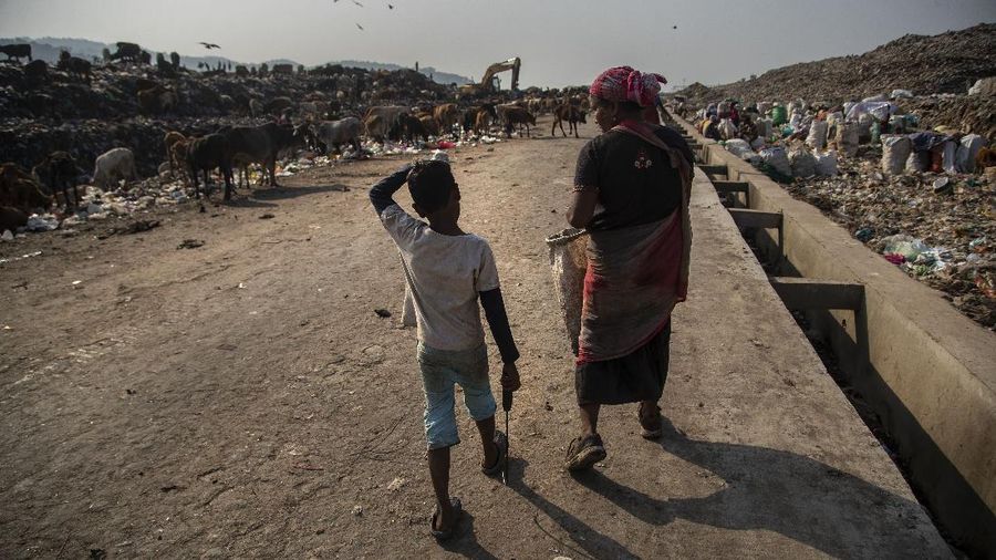 Imradul Ali, 10, left, and his mother Anuwara Beghum, 30, take a break as they look for recyclable material at a landfill on the outskirts of Gauhati, India, Thursday, Feb. 4, 2021. Once school is done for the day, Ali, rushes home to change out of his uniform so that he can start his job as a scavenger in India’s remote northeast. Coming from a family of scavengers or “rag pickers,