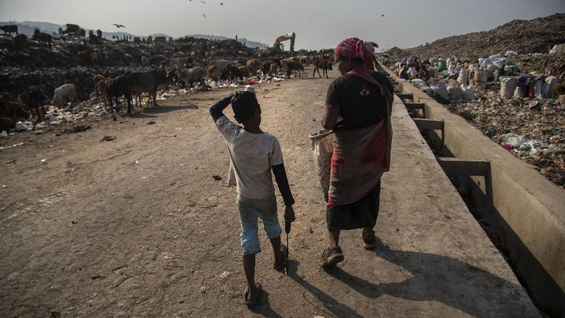 Imradul Ali, 10, left, and his mother Anuwara Beghum, 30, take a break as they look for recyclable material at a landfill on the outskirts of Gauhati, India, Thursday, Feb. 4, 2021. Once school is done for the day, Ali, rushes home to change out of his uniform so that he can start his job as a scavenger in India’s remote northeast. Coming from a family of scavengers or “rag pickers,