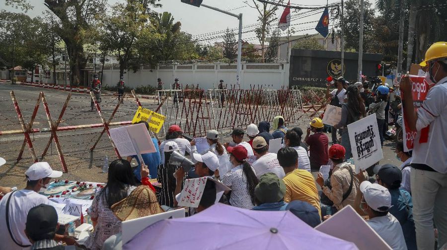 A policeman stands guard as demonstrators display placards during a protest close to Indonesian embassy in Yangon, Myanmar Tuesday, Feb. 23, 2021. Anti-coup protesters gathered outside the Indonesian Embassy following reports that Indonesia was seeking to have fellow members of the Association of Southeast Asian Nations to agree on an action plan over the Myanmar’s coup that would hold the junta  to its promise to hold free and fair elections in a year's time. The Indonesia Foreign Ministry has denied the report. (AP Photo)