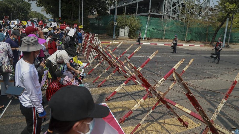 A policeman stands guard as demonstrators display placards during a protest close to Indonesian embassy in Yangon, Myanmar Tuesday, Feb. 23, 2021. Anti-coup protesters gathered outside the Indonesian Embassy following reports that Indonesia was seeking to have fellow members of the Association of Southeast Asian Nations to agree on an action plan over the Myanmar’s coup that would hold the junta  to its promise to hold free and fair elections in a year's time. The Indonesia Foreign Ministry has denied the report. (AP Photo)