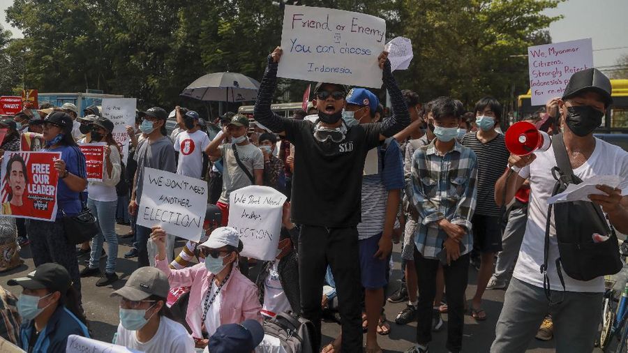 A policeman stands guard as demonstrators display placards during a protest close to Indonesian embassy in Yangon, Myanmar Tuesday, Feb. 23, 2021. Anti-coup protesters gathered outside the Indonesian Embassy following reports that Indonesia was seeking to have fellow members of the Association of Southeast Asian Nations to agree on an action plan over the Myanmar’s coup that would hold the junta  to its promise to hold free and fair elections in a year's time. The Indonesia Foreign Ministry has denied the report. (AP Photo)