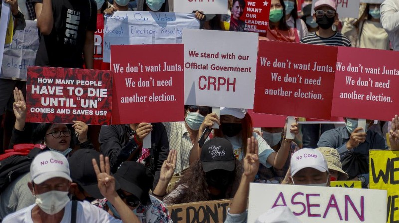 A policeman stands guard as demonstrators display placards during a protest close to Indonesian embassy in Yangon, Myanmar Tuesday, Feb. 23, 2021. Anti-coup protesters gathered outside the Indonesian Embassy following reports that Indonesia was seeking to have fellow members of the Association of Southeast Asian Nations to agree on an action plan over the Myanmar’s coup that would hold the junta  to its promise to hold free and fair elections in a year's time. The Indonesia Foreign Ministry has denied the report. (AP Photo)