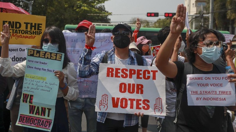 A policeman stands guard as demonstrators display placards during a protest close to Indonesian embassy in Yangon, Myanmar Tuesday, Feb. 23, 2021. Anti-coup protesters gathered outside the Indonesian Embassy following reports that Indonesia was seeking to have fellow members of the Association of Southeast Asian Nations to agree on an action plan over the Myanmar’s coup that would hold the junta  to its promise to hold free and fair elections in a year's time. The Indonesia Foreign Ministry has denied the report. (AP Photo)