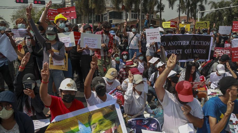A policeman stands guard as demonstrators display placards during a protest close to Indonesian embassy in Yangon, Myanmar Tuesday, Feb. 23, 2021. Anti-coup protesters gathered outside the Indonesian Embassy following reports that Indonesia was seeking to have fellow members of the Association of Southeast Asian Nations to agree on an action plan over the Myanmar’s coup that would hold the junta  to its promise to hold free and fair elections in a year's time. The Indonesia Foreign Ministry has denied the report. (AP Photo)