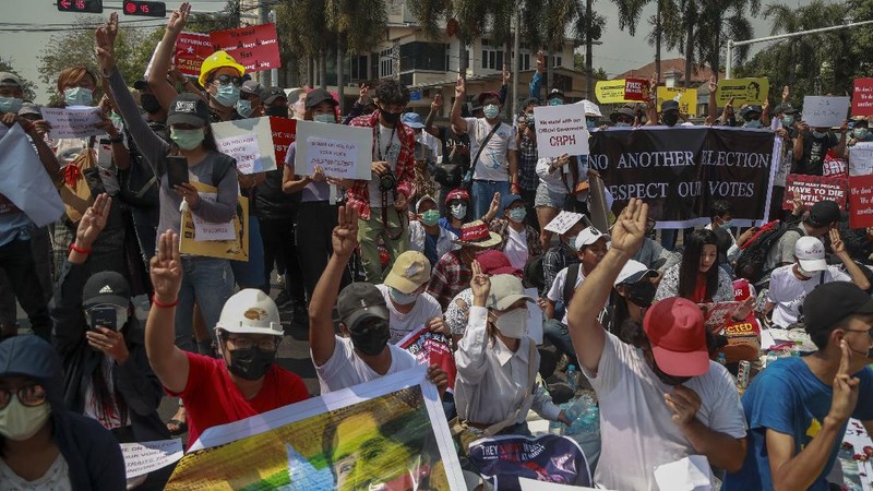 A policeman stands guard as demonstrators display placards during a protest close to Indonesian embassy in Yangon, Myanmar Tuesday, Feb. 23, 2021. Anti-coup protesters gathered outside the Indonesian Embassy following reports that Indonesia was seeking to have fellow members of the Association of Southeast Asian Nations to agree on an action plan over the Myanmar’s coup that would hold the junta  to its promise to hold free and fair elections in a year's time. The Indonesia Foreign Ministry has denied the report. (AP Photo)
