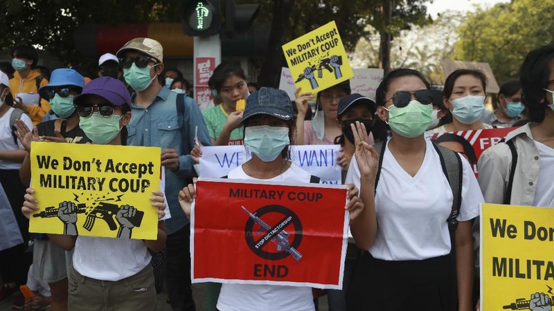 A policeman stands guard as demonstrators display placards during a protest close to Indonesian embassy in Yangon, Myanmar Tuesday, Feb. 23, 2021. Anti-coup protesters gathered outside the Indonesian Embassy following reports that Indonesia was seeking to have fellow members of the Association of Southeast Asian Nations to agree on an action plan over the Myanmar’s coup that would hold the junta  to its promise to hold free and fair elections in a year's time. The Indonesia Foreign Ministry has denied the report. (AP Photo)