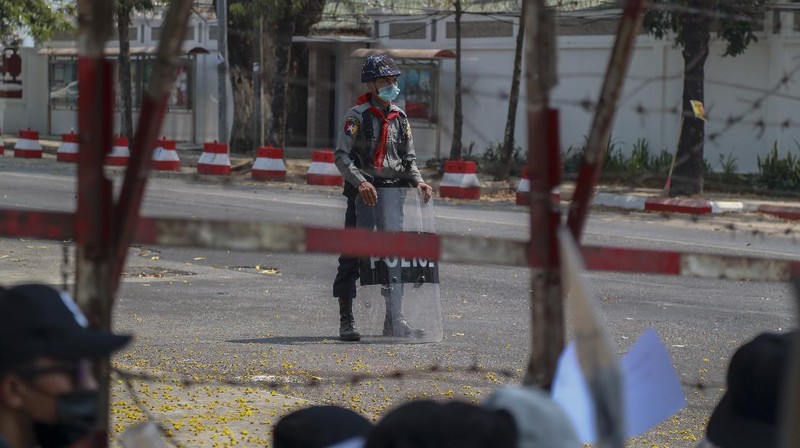 A policeman stands guard as demonstrators display placards during a protest close to Indonesian embassy in Yangon, Myanmar Tuesday, Feb. 23, 2021. Anti-coup protesters gathered outside the Indonesian Embassy following reports that Indonesia was seeking to have fellow members of the Association of Southeast Asian Nations to agree on an action plan over the Myanmar’s coup that would hold the junta  to its promise to hold free and fair elections in a year's time. The Indonesia Foreign Ministry has denied the report. (AP Photo)