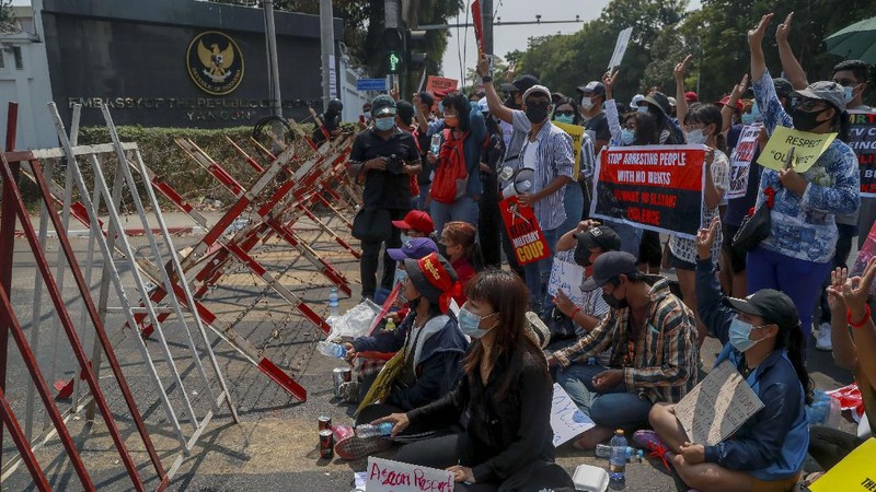 A policeman stands guard as demonstrators display placards during a protest close to Indonesian embassy in Yangon, Myanmar Tuesday, Feb. 23, 2021. Anti-coup protesters gathered outside the Indonesian Embassy following reports that Indonesia was seeking to have fellow members of the Association of Southeast Asian Nations to agree on an action plan over the Myanmar’s coup that would hold the junta  to its promise to hold free and fair elections in a year's time. The Indonesia Foreign Ministry has denied the report. (AP Photo)