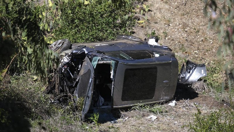 Workers collect debris beside a vehicle after a rollover accident involving golfer Tiger Woods Tuesday, Feb. 23, 2021, in Rancho Palos Verdes, Calif., a suburb of Los Angeles. Woods suffered leg injuries in the one-car accident and was undergoing surgery, authorities and his manager said. (AP Photo/Marcio Jose Sanchez)