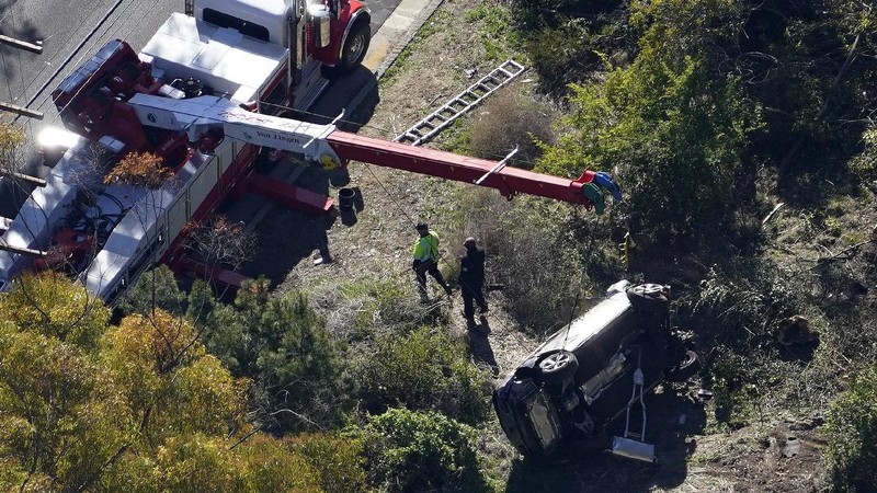 Workers collect debris beside a vehicle after a rollover accident involving golfer Tiger Woods Tuesday, Feb. 23, 2021, in Rancho Palos Verdes, Calif., a suburb of Los Angeles. Woods suffered leg injuries in the one-car accident and was undergoing surgery, authorities and his manager said. (AP Photo/Marcio Jose Sanchez)