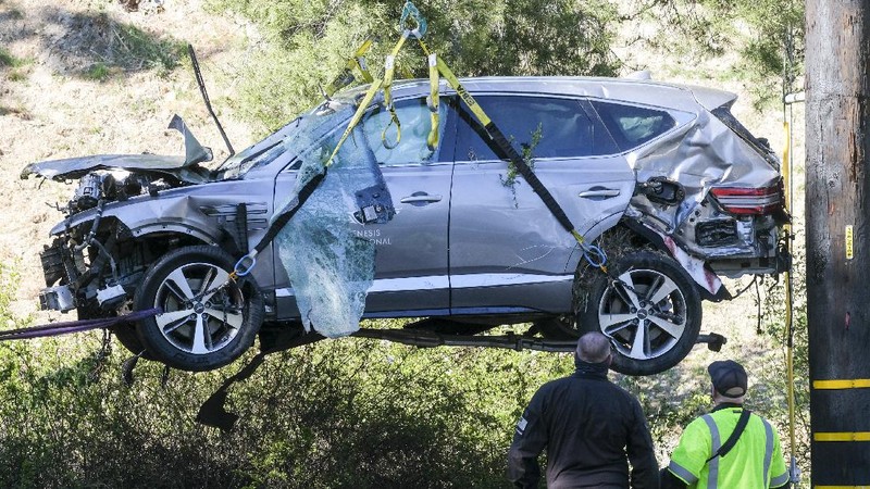 Workers collect debris beside a vehicle after a rollover accident involving golfer Tiger Woods Tuesday, Feb. 23, 2021, in Rancho Palos Verdes, Calif., a suburb of Los Angeles. Woods suffered leg injuries in the one-car accident and was undergoing surgery, authorities and his manager said. (AP Photo/Marcio Jose Sanchez)