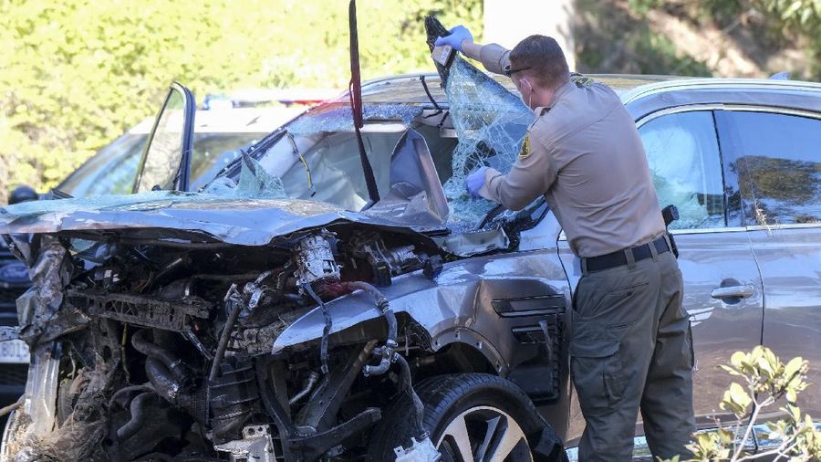 Workers collect debris beside a vehicle after a rollover accident involving golfer Tiger Woods Tuesday, Feb. 23, 2021, in Rancho Palos Verdes, Calif., a suburb of Los Angeles. Woods suffered leg injuries in the one-car accident and was undergoing surgery, authorities and his manager said. (AP Photo/Marcio Jose Sanchez)
