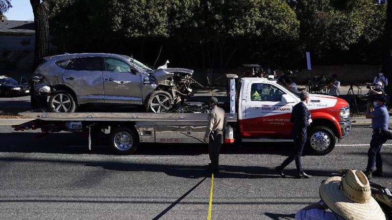 Workers collect debris beside a vehicle after a rollover accident involving golfer Tiger Woods Tuesday, Feb. 23, 2021, in Rancho Palos Verdes, Calif., a suburb of Los Angeles. Woods suffered leg injuries in the one-car accident and was undergoing surgery, authorities and his manager said. (AP Photo/Marcio Jose Sanchez)