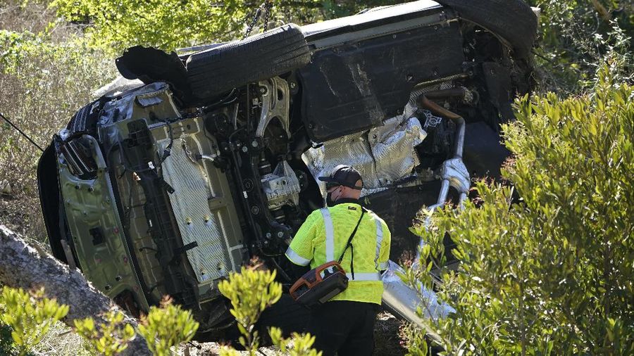 Workers collect debris beside a vehicle after a rollover accident involving golfer Tiger Woods Tuesday, Feb. 23, 2021, in Rancho Palos Verdes, Calif., a suburb of Los Angeles. Woods suffered leg injuries in the one-car accident and was undergoing surgery, authorities and his manager said. (AP Photo/Marcio Jose Sanchez)