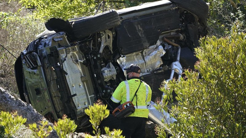 Workers collect debris beside a vehicle after a rollover accident involving golfer Tiger Woods Tuesday, Feb. 23, 2021, in Rancho Palos Verdes, Calif., a suburb of Los Angeles. Woods suffered leg injuries in the one-car accident and was undergoing surgery, authorities and his manager said. (AP Photo/Marcio Jose Sanchez)