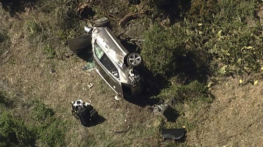Workers collect debris beside a vehicle after a rollover accident involving golfer Tiger Woods Tuesday, Feb. 23, 2021, in Rancho Palos Verdes, Calif., a suburb of Los Angeles. Woods suffered leg injuries in the one-car accident and was undergoing surgery, authorities and his manager said. (AP Photo/Marcio Jose Sanchez)