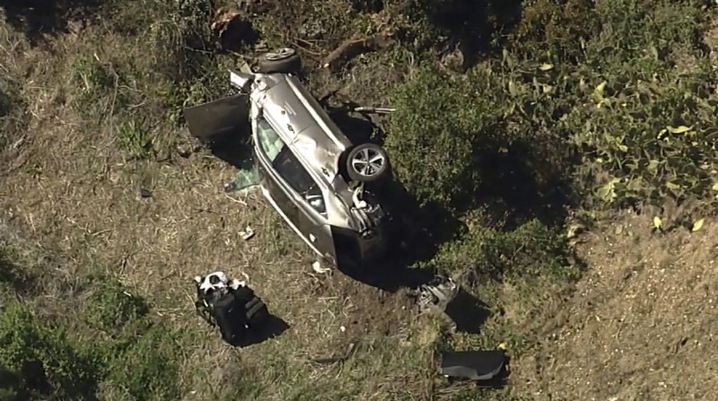 Workers collect debris beside a vehicle after a rollover accident involving golfer Tiger Woods Tuesday, Feb. 23, 2021, in Rancho Palos Verdes, Calif., a suburb of Los Angeles. Woods suffered leg injuries in the one-car accident and was undergoing surgery, authorities and his manager said. (AP Photo/Marcio Jose Sanchez)
