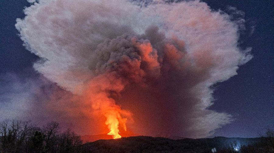 A fiery river of glowing lava flows on the north-east side of the Mt Etna volcano engulfed with ashes and smoke near Milo, Sicily, Wednesday night, Feb. 24, 2021. Europe's most active volcano has been steadily erupting since last week, belching smoke, ash, and fountains of red-hot lava. (AP Photo/Salvatore Allegra)