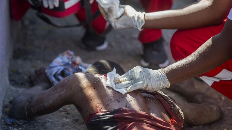 Students rush past the bodies of inmates outside the Croix-des-Bouquets Civil Prison after an attempted breakout in Port-au-Prince, Haiti, Thursday, Feb. 25, 2021. At least seven people were killed and one injured on Thursday after eyewitnesses told The Associated Press that several inmates tried to escape. (AP Photo/Dieu Nalio Chery).