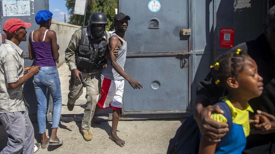 Students rush past the bodies of inmates outside the Croix-des-Bouquets Civil Prison after an attempted breakout in Port-au-Prince, Haiti, Thursday, Feb. 25, 2021. At least seven people were killed and one injured on Thursday after eyewitnesses told The Associated Press that several inmates tried to escape. (AP Photo/Dieu Nalio Chery).