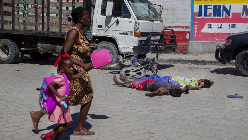 Students rush past the bodies of inmates outside the Croix-des-Bouquets Civil Prison after an attempted breakout in Port-au-Prince, Haiti, Thursday, Feb. 25, 2021. At least seven people were killed and one injured on Thursday after eyewitnesses told The Associated Press that several inmates tried to escape. (AP Photo/Dieu Nalio Chery).