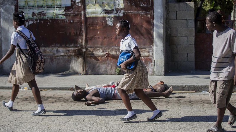 Students rush past the bodies of inmates outside the Croix-des-Bouquets Civil Prison after an attempted breakout in Port-au-Prince, Haiti, Thursday, Feb. 25, 2021. At least seven people were killed and one injured on Thursday after eyewitnesses told The Associated Press that several inmates tried to escape. (AP Photo/Dieu Nalio Chery).