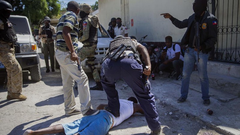 Students rush past the bodies of inmates outside the Croix-des-Bouquets Civil Prison after an attempted breakout in Port-au-Prince, Haiti, Thursday, Feb. 25, 2021. At least seven people were killed and one injured on Thursday after eyewitnesses told The Associated Press that several inmates tried to escape. (AP Photo/Dieu Nalio Chery).