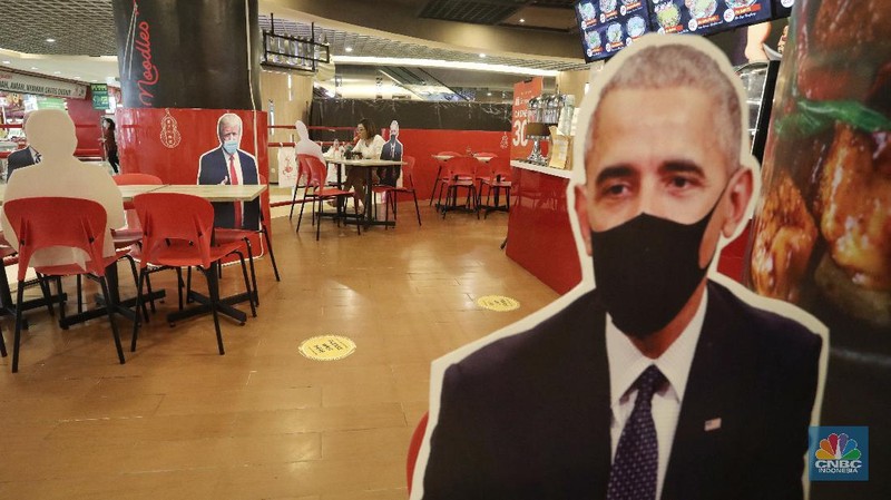 Pengunjung menikmati makanan disamping pembatas jarak bergambar karakter Presiden Amerika Serikat Joe Biden yang menghiasi salah satu pusat restoran cepat saji  di kawasan Kuningan, Jakarta, Selasa (2/3/2021). (CNBC Indonesia/Andrean Kristianto)