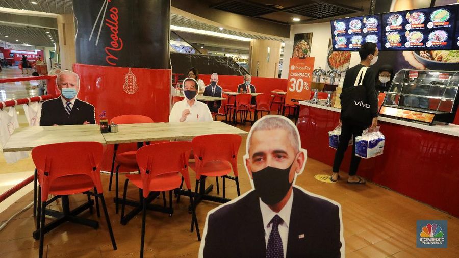 Pengunjung menikmati makanan disamping pembatas jarak bergambar karakter Presiden Amerika Serikat Joe Biden yang menghiasi salah satu pusat restoran cepat saji  di kawasan Kuningan, Jakarta, Selasa (2/3/2021). (CNBC Indonesia/Andrean Kristianto)