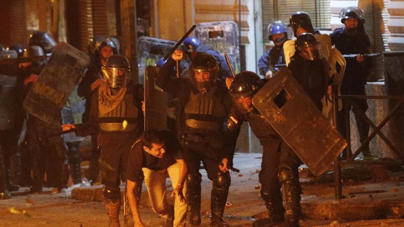 A protester slips in clashes with police during protest against the government of President Mario Abdo Benitez in response to the shortage of medications for COVID-19 patients in hospitals and the low availability of the vaccine against the new coronavirus, amid the resignation of the country's health minister, in Asuncion, Paraguay, Friday, March 5, 2021. (AP Photo/Jorge Saenz)