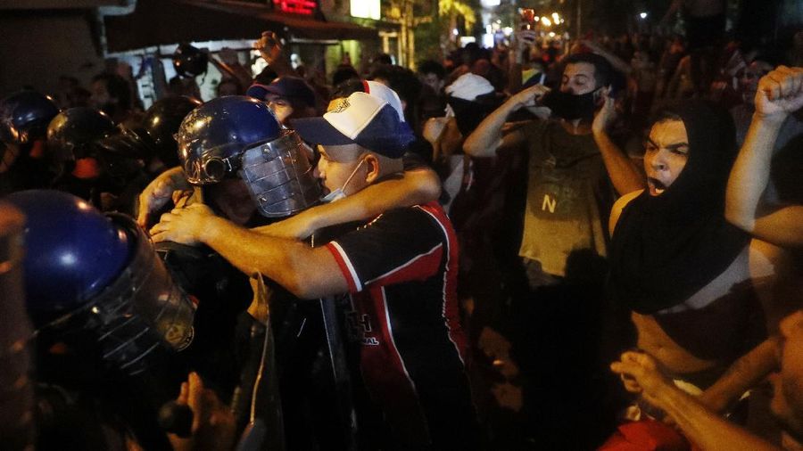 A protester slips in clashes with police during protest against the government of President Mario Abdo Benitez in response to the shortage of medications for COVID-19 patients in hospitals and the low availability of the vaccine against the new coronavirus, amid the resignation of the country's health minister, in Asuncion, Paraguay, Friday, March 5, 2021. (AP Photo/Jorge Saenz)
