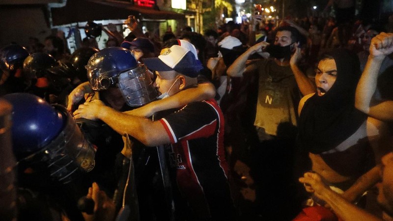 A protester slips in clashes with police during protest against the government of President Mario Abdo Benitez in response to the shortage of medications for COVID-19 patients in hospitals and the low availability of the vaccine against the new coronavirus, amid the resignation of the country's health minister, in Asuncion, Paraguay, Friday, March 5, 2021. (AP Photo/Jorge Saenz)