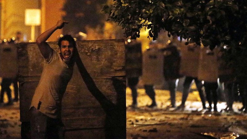 A protester slips in clashes with police during protest against the government of President Mario Abdo Benitez in response to the shortage of medications for COVID-19 patients in hospitals and the low availability of the vaccine against the new coronavirus, amid the resignation of the country's health minister, in Asuncion, Paraguay, Friday, March 5, 2021. (AP Photo/Jorge Saenz)