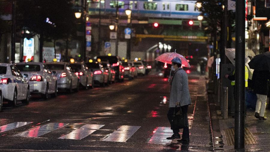People wearing protective masks to help curb the spread of the coronavirus run along a pedestrian crossing Thursday, Feb. 25, 2021, in Tokyo. The Japanese capital confirmed more than 340 new coronavirus cases on Thursday. (AP Photo/Eugene Hoshiko)