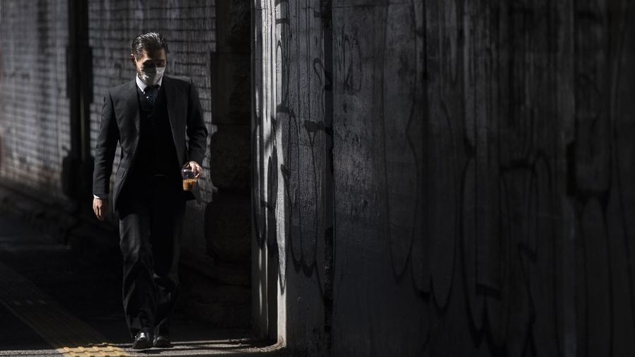 A man wearing a face mask walks on a street during lunchtime in Tokyo on Thursday, March 4, 2021. (AP Photo/Hiro Komae)