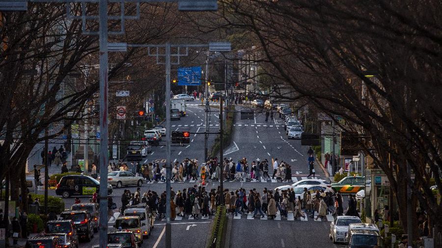 People wearing protective masks to help curb the spread of the coronavirus run along a pedestrian crossing Thursday, Feb. 25, 2021, in Tokyo. The Japanese capital confirmed more than 340 new coronavirus cases on Thursday. (AP Photo/Eugene Hoshiko)