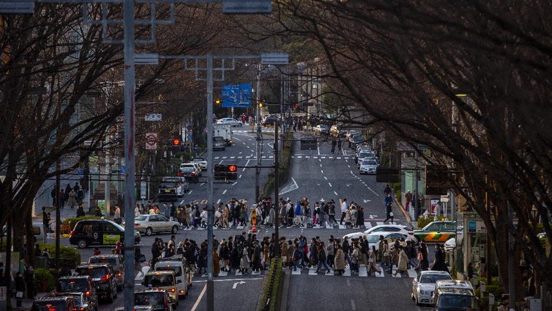 People wearing protective masks to help curb the spread of the coronavirus run along a pedestrian crossing Thursday, Feb. 25, 2021, in Tokyo. The Japanese capital confirmed more than 340 new coronavirus cases on Thursday. (AP Photo/Eugene Hoshiko)