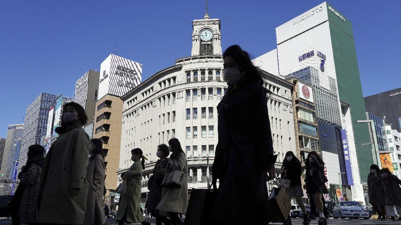 People wearing protective masks to help curb the spread of the coronavirus run along a pedestrian crossing Thursday, Feb. 25, 2021, in Tokyo. The Japanese capital confirmed more than 340 new coronavirus cases on Thursday. (AP Photo/Eugene Hoshiko)