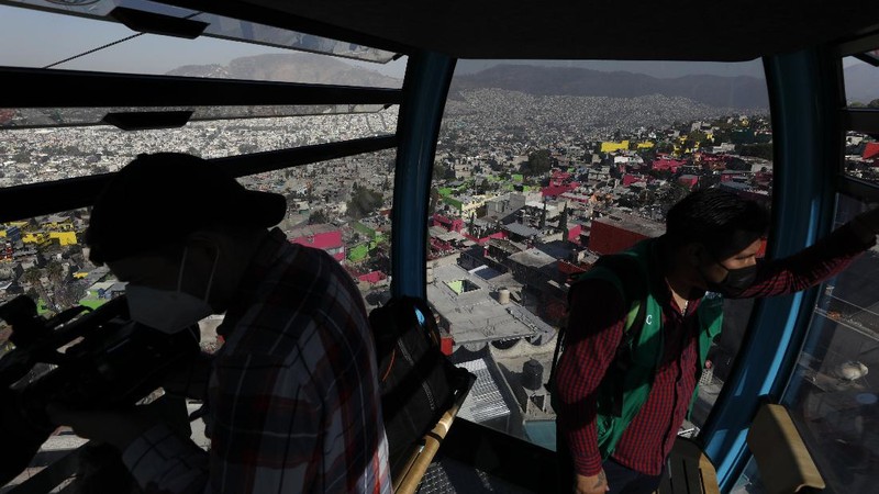 Officials and journalists ride in cable cars between the Campos Revolucion and Tlalpexco stations, during the inauguration of a new aerial public transit system dubbed the Cablebus, in the Cuautepec neighborhood of northern Mexico City, Thursday, March 4, 2021. For the residents of Cuautepec, this new system, the first of four planned lines, will turn a commute to the nearest subway station, that can last up to two hours, into a 30-minute ride. (AP Photo/Rebecca Blackwell)
