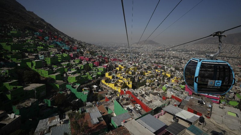 Officials and journalists ride in cable cars between the Campos Revolucion and Tlalpexco stations, during the inauguration of a new aerial public transit system dubbed the Cablebus, in the Cuautepec neighborhood of northern Mexico City, Thursday, March 4, 2021. For the residents of Cuautepec, this new system, the first of four planned lines, will turn a commute to the nearest subway station, that can last up to two hours, into a 30-minute ride. (AP Photo/Rebecca Blackwell)
