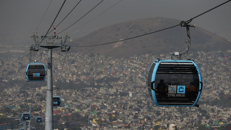 Officials and journalists ride in cable cars between the Campos Revolucion and Tlalpexco stations, during the inauguration of a new aerial public transit system dubbed the Cablebus, in the Cuautepec neighborhood of northern Mexico City, Thursday, March 4, 2021. For the residents of Cuautepec, this new system, the first of four planned lines, will turn a commute to the nearest subway station, that can last up to two hours, into a 30-minute ride. (AP Photo/Rebecca Blackwell)