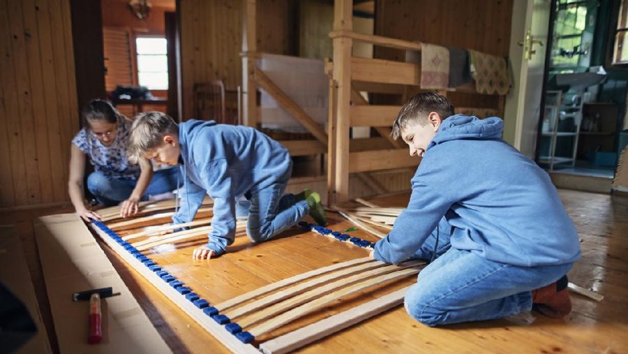 Brothers and sister assembling bed base together.
Nikon D850