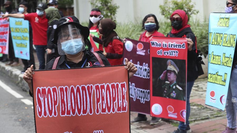 Labor activists destroy a poster of a defaced image of Commander in Chief, Sen. Gen. Min Aung Hlaing during a protest outside the Embassy of Myanmar in Jakarta, Indonesia , Wednesday, March 10, 2021. Dozens of Indonesian labor activists angered over the military coup in Myanmar protested Wednesday outside the Myanmar Embassy in the Indonesian capital. (AP Photo/Achmad Ibrahim)