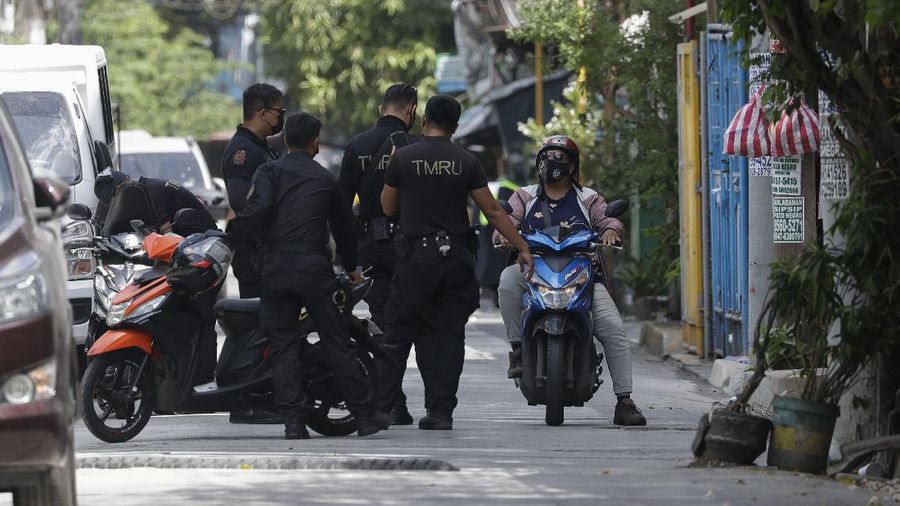 A cat crosses an empty street at a village that was placed under lockdown due to the number of COVID-19 cases among residents in Manila, Philippines on Thursday, March 11, 2021. The Philippine capital placed two villages and two hotels on lockdown Thursday and police have renewed warnings against kissing and other