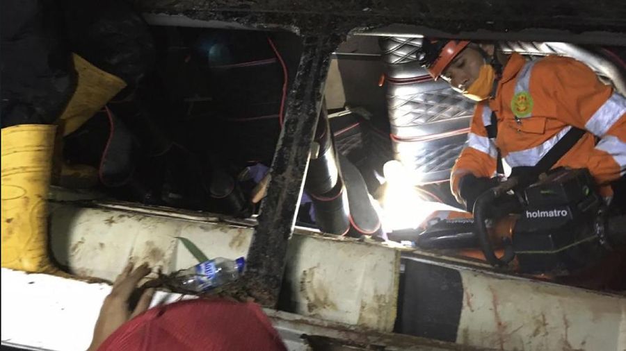 In this photo released by National Search and Rescue Agency (BASARNAS), rescuers search for survivors and victims inside the wreckage of a bus that plunged into a ravine in Sumedang West Java, Indonesia, Thursday, March 11, 2021. The tourist bus plunged into the ravine after its brakes apparently malfunctioned, killing a number of people, police and rescuers said. (BASARNAS via AP)