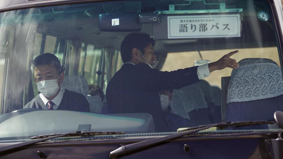 Fumio Ito, head of public relations at Minami Sanriku Hotel Kanyo, tells his experience of 2011 tsunami disaster in the area to participants inside a bus during the 