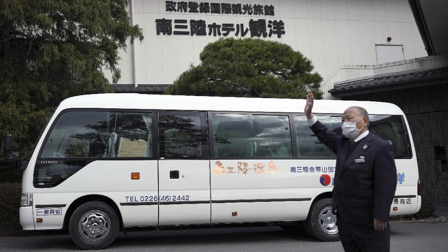 Fumio Ito, head of public relations at Minami Sanriku Hotel Kanyo, tells his experience of 2011 tsunami disaster in the area to participants inside a bus during the 