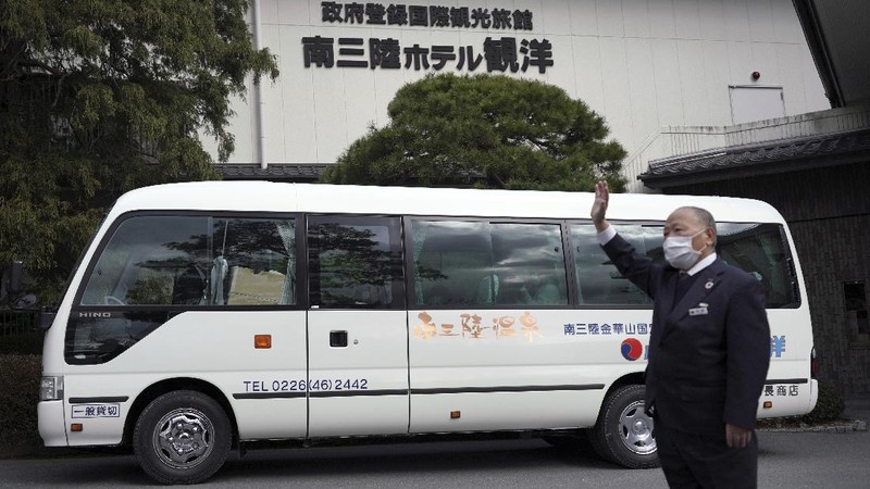 Fumio Ito, head of public relations at Minami Sanriku Hotel Kanyo, tells his experience of 2011 tsunami disaster in the area to participants inside a bus during the 